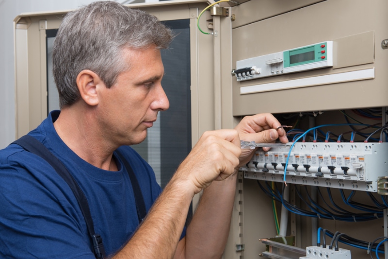 5 Reasons to Upgrade Your Electrical Panel. Repairman Fixing An Electric Switchboard Indoor.
